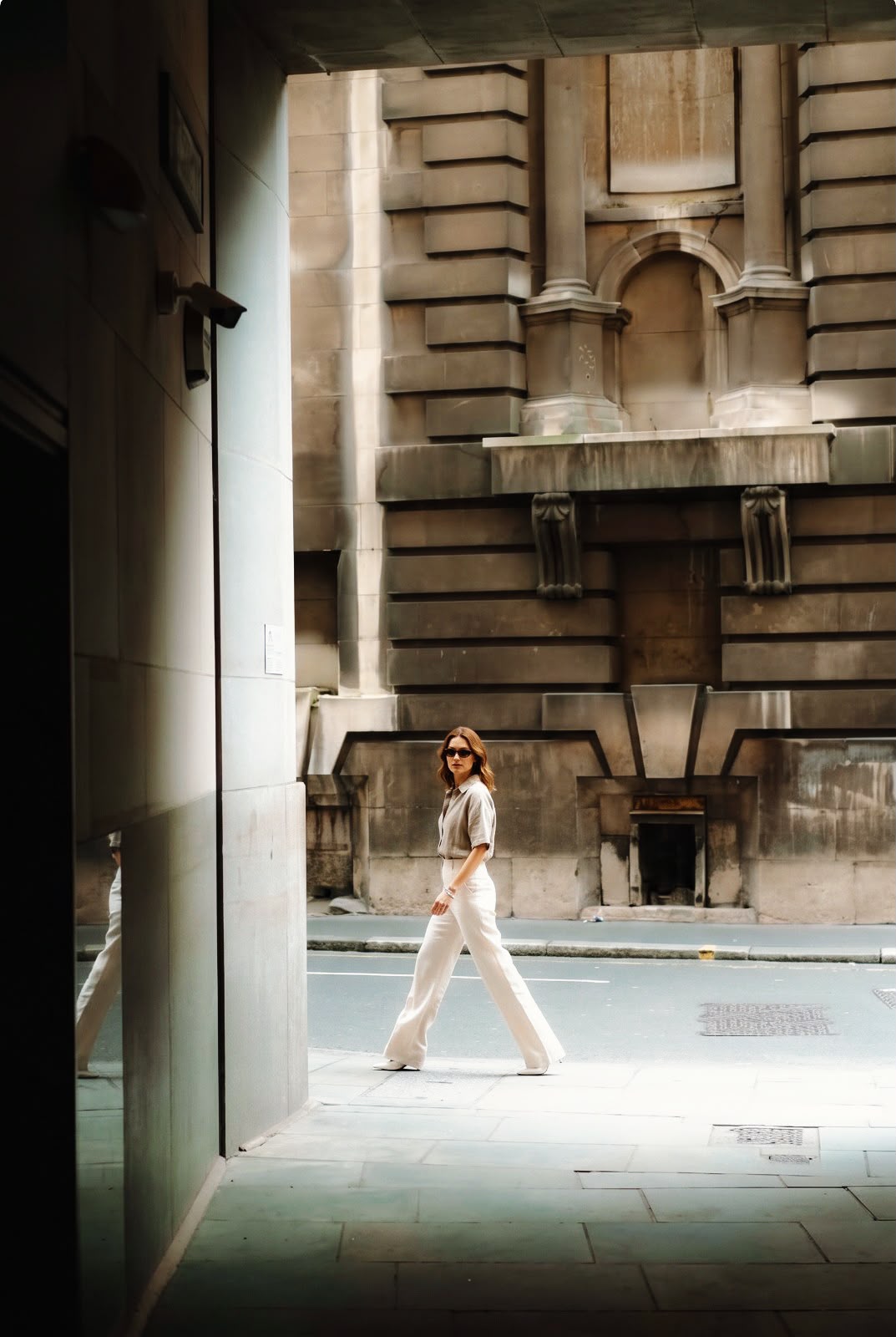 Customer in white high-waist wide-leg trousers walking through the city